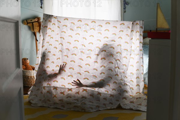 Shadows of children behind bedding tent in nursery