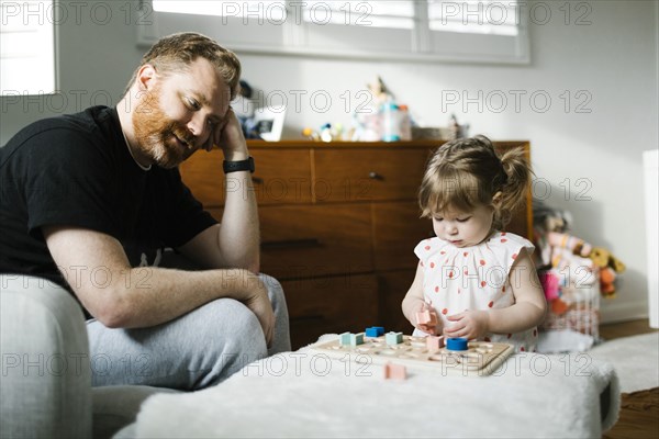 Father watching daughter (2-3) play