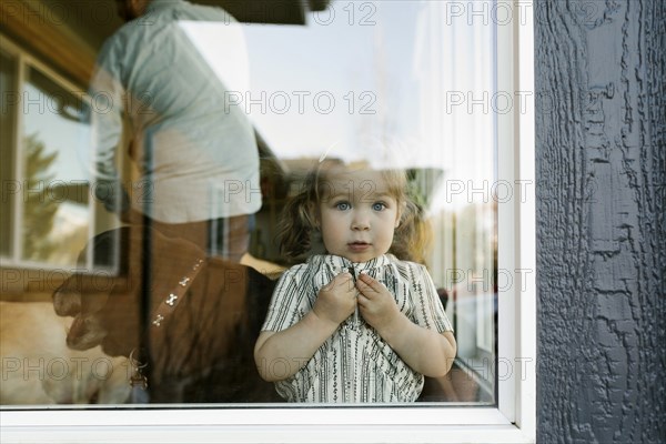 Girl (2-3) looking through window