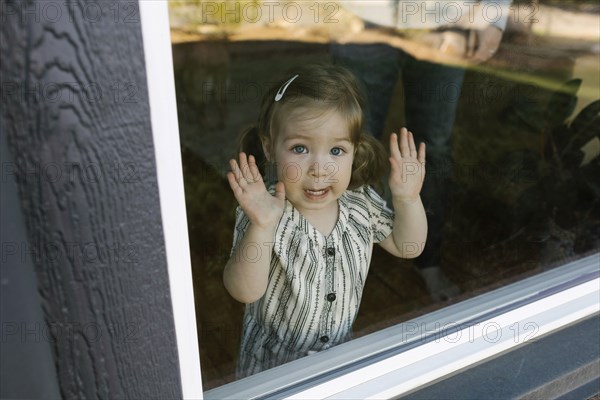 Girl (2-3) looking through window