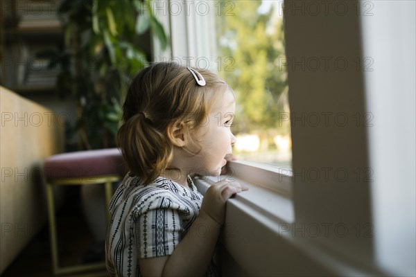 Girl (2-3) looking through window