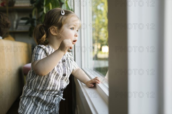 Girl (2-3) looking through window