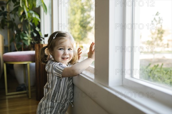 Girl (2-3) standing at window