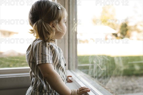 Girl (2-3) looking through window