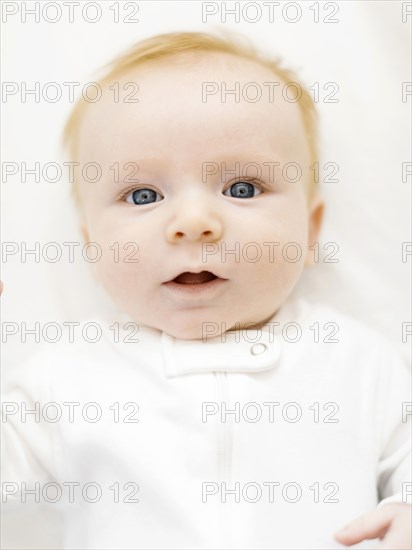 Portrait of baby boy (2-3 months) lying on bed