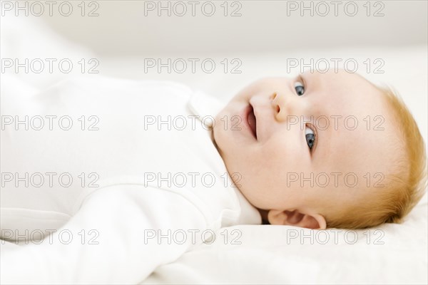 Portrait of baby boy (2-3 months) lying on bed