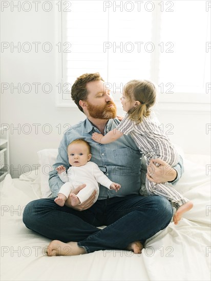 Father sitting on bed with children (2-3 months, 2-3)