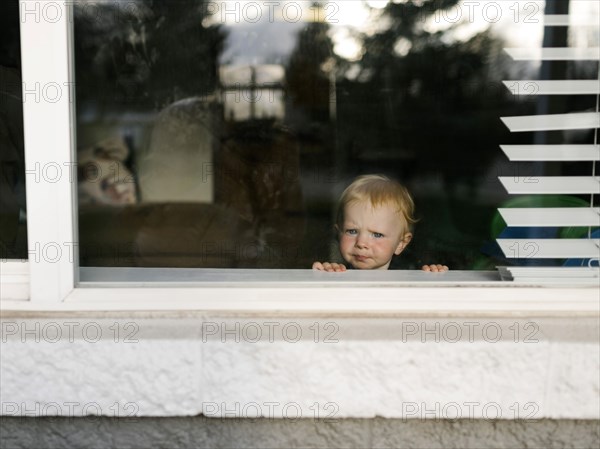 Girl (2-3) looking through window