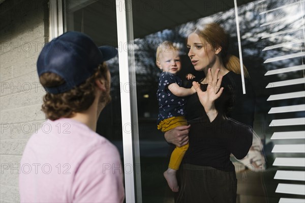Mother with daughter (2-3) talking to man through window