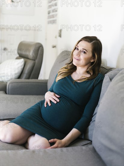 Portrait of pregnant woman sitting on sofa