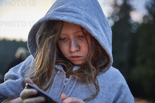 Girl in hoodie using phone