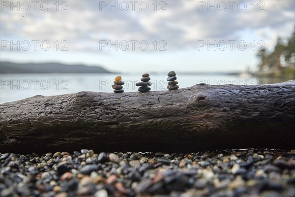 USA, Washington, San Juan County, Orcas Island, Stacks of pebbles on log