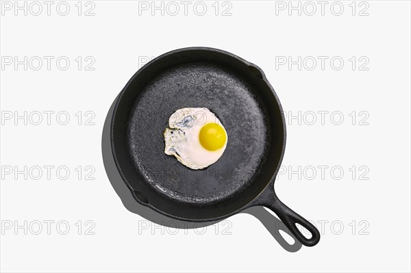 Overhead view of fried egg on frying pan on white background