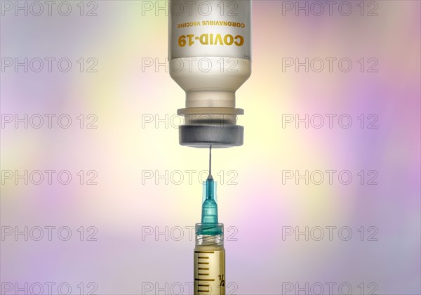 Covid-19 vaccine and syringe on colorful background