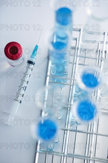 Overhead view of test tubes with blue liquid and syringe