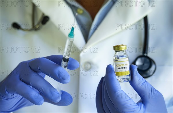 Close-up of doctors hands holding Covid1-19 vaccine and syringe