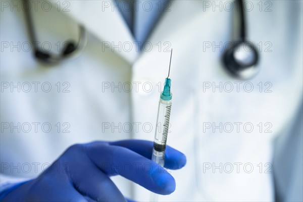 Close-up of gloved doctors hand holding syringe