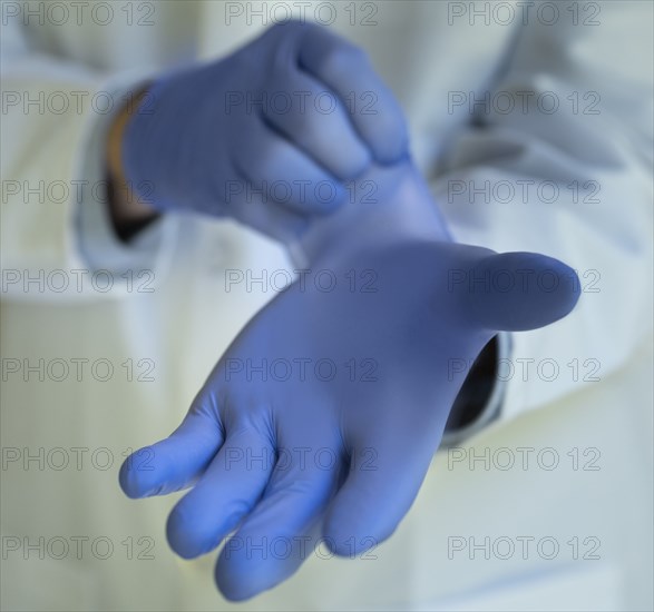 Close-up of doctor putting on blue latex gloves