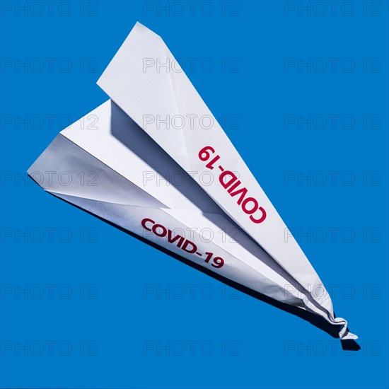 Studio shot of paper plane with Covid-19 sign