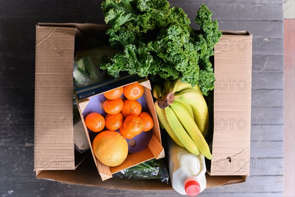 Overhead view of box of delivered produce on house porch