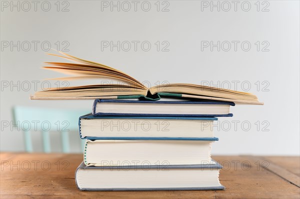 Open book on top of stack of books on desk