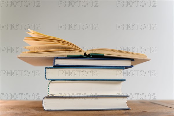 Open book on top of stack of books on desk