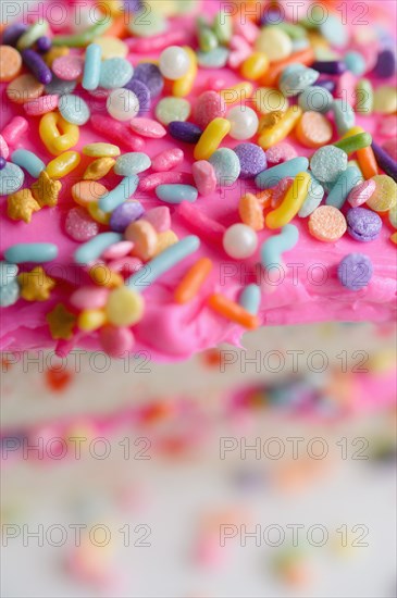 Colorful sprinkles on pink cake frosting