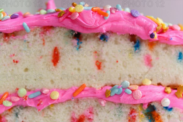 Colorful sprinkles on pink cake frosting