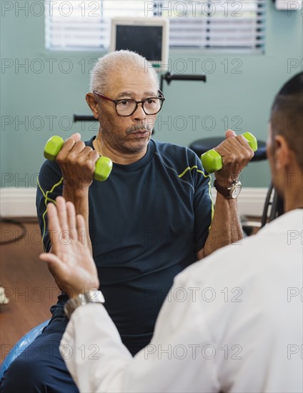 Senior man exercising with therapist during physical therapy