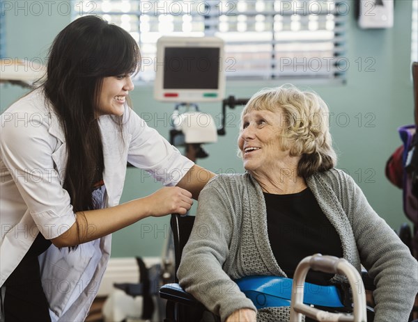 Nurse assisting senior woman in wheelchair in retirement home