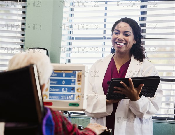 Doctor holding tablet and talking to senior man during exercising