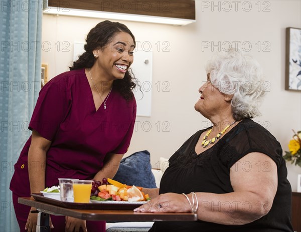 Nurse bringing healthy meal to senior woman