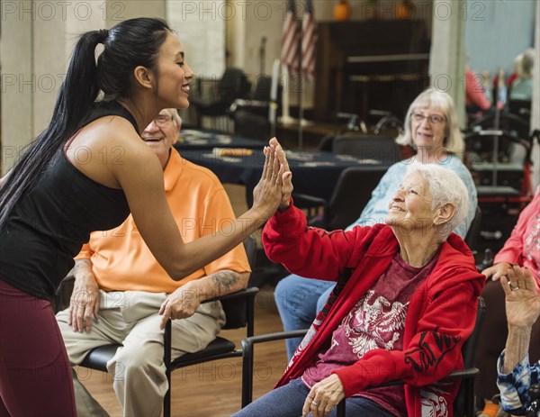 Senior woman high-fiving fitness instructor