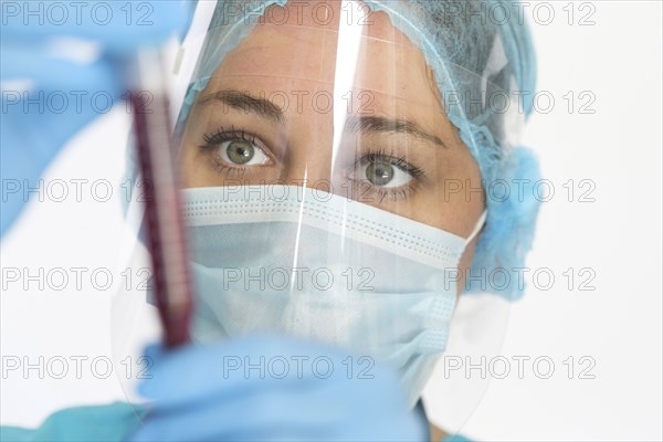 Nurse in mask and face shield holding blood sample