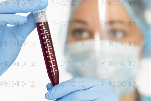 Nurse in mask and face shield holding blood sample