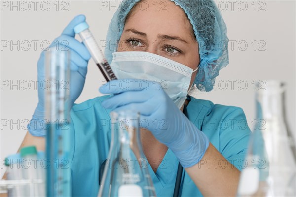 Laboratory technician in face mask holding blood sample
