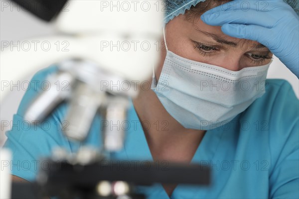 Laboratory technician frowning behind microscope