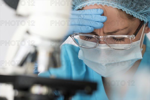 Healthcare professional with face mask using microscope