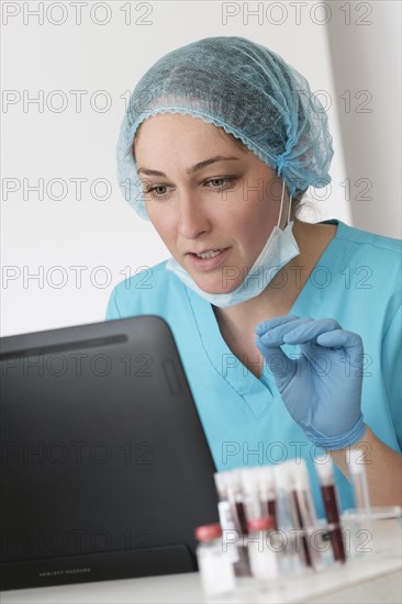 Woman in protective lab workwear sitting in front of laptop