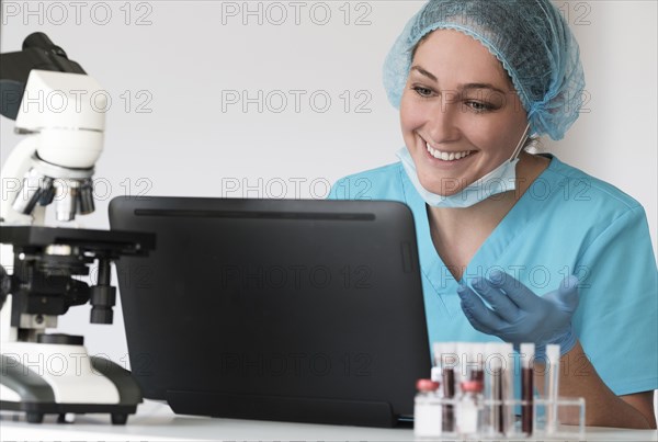 Woman in protective lab workwear sitting in front of laptop