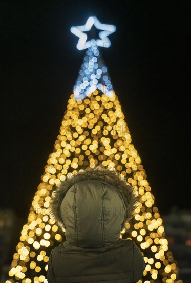 Boy in front of illuminated Christmas tree