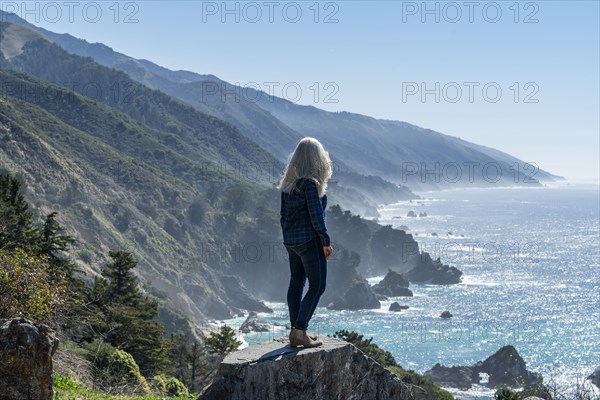 USA, California, Big Sur, Woman standing at the edge of cliff looking at view