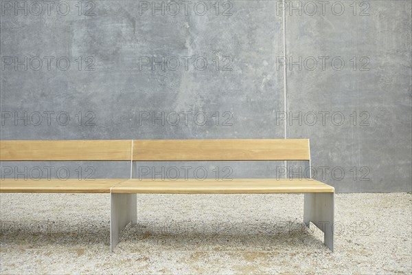 Wooden modern bench against concrete wall