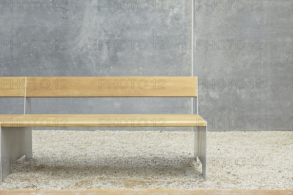 Wooden modern bench against concrete wall