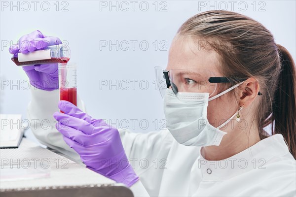 Female technician pouring liquid into vial
