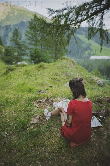 Switzerland, Obergoms, Young woman painting with watercolor in Swiss Alps