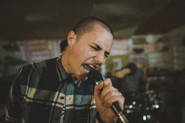 Young man singing during rehearsal in garage