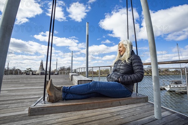 USA, Washington D.C., Senior woman on swing at Wharf District along Potomac River