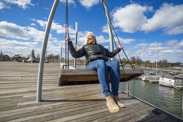 USA, Washington D.C., Senior woman on swing at Wharf District along Potomac River