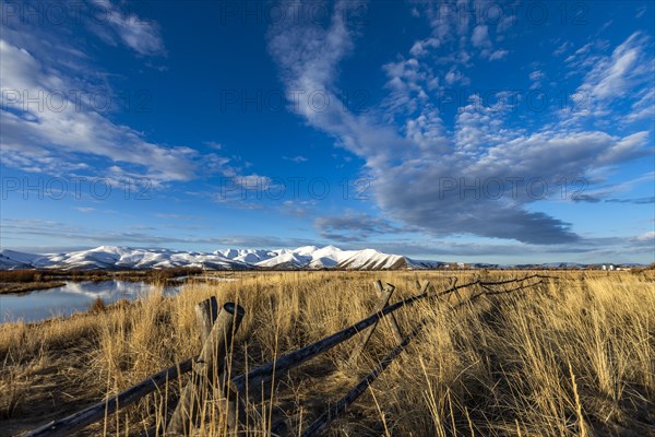 USA, Idaho, Sun Valley, Landscape with fence, grass and snowy mountain in background